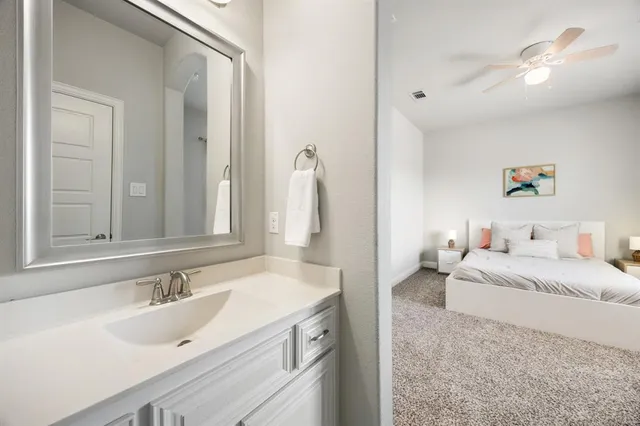 a spacious bedroom with a double vanity sink and a mirror