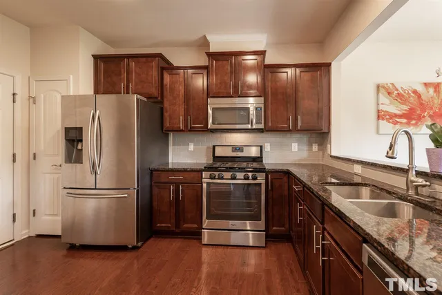 a kitchen with stainless steel appliances granite countertop a refrigerator stove and sink