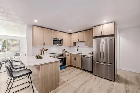 a kitchen with a refrigerator a stove top oven a sink dishwasher and white cabinets with wooden floor