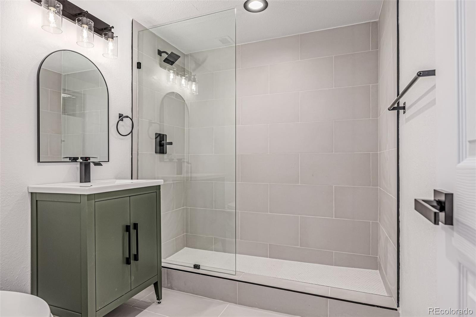 3831 West Rutgers Place Denver, CO 80236 - Photo 26 of 35 a bathroom with a shower a sink and mirror