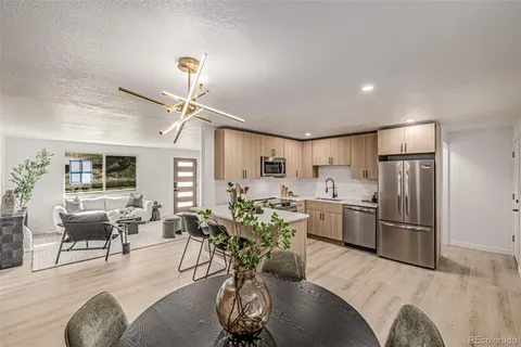 a living room with furniture a chandelier and kitchen view