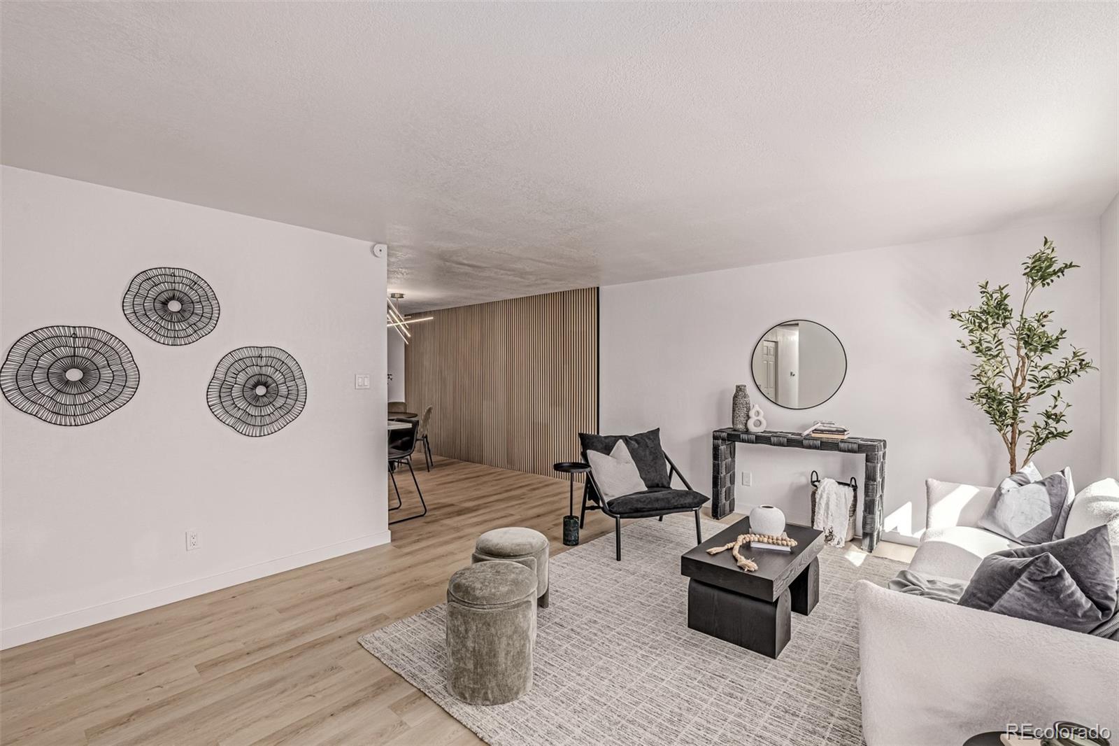 3831 West Rutgers Place Denver, CO 80236 - Photo 7 of 35 a living room with furniture a clock and a wooden floor