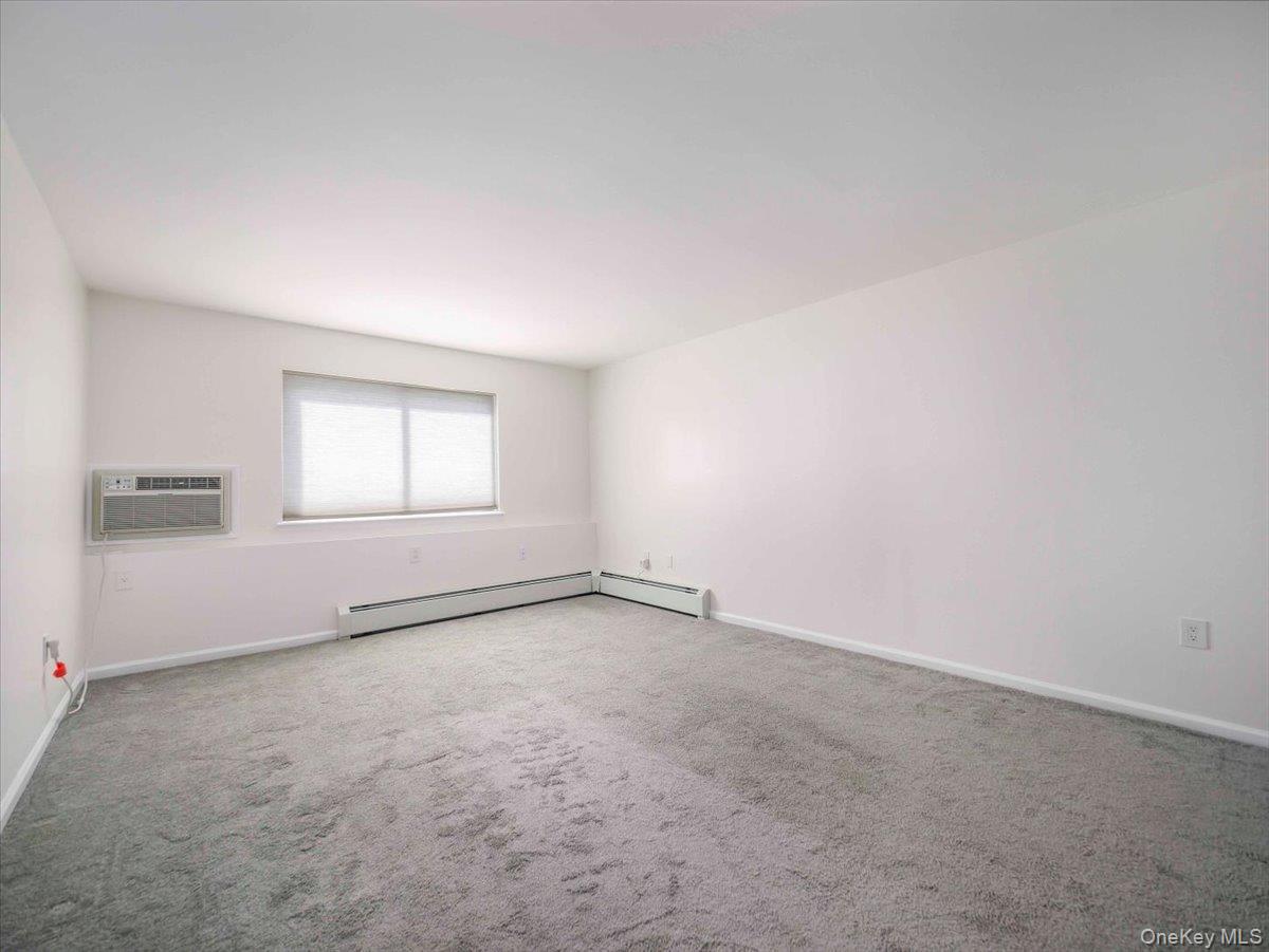27 Tanager Road, Unit 2702 Monroe, NY 10950 - Photo 19 of 35 Carpeted interior space with a window, window-mounted air conditioning unit, and baseboard heating