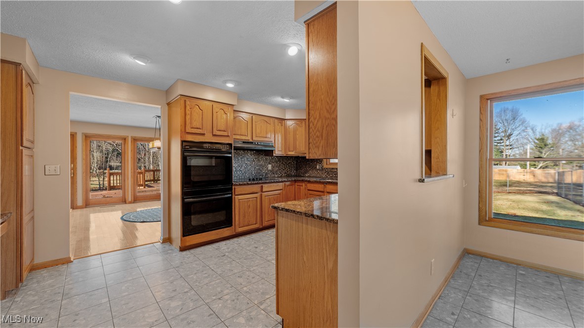 546 Twitchell Road Mansfield, OH 44903 - Photo 12 of 47 Kitchen featuring dark stone counters, backsplash, a wealth of natural light, and black appliances
