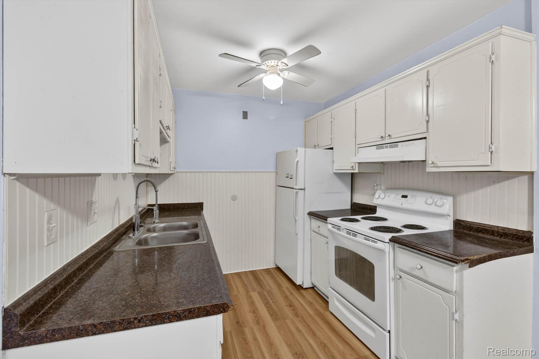 25301 Five Mile Road, Unit 109 Redford, MI 48239 - Photo 13 of 22 Kitchen with white electric range oven, dark countertops, a wainscoted wall, ceiling fan, and light wood-style floors