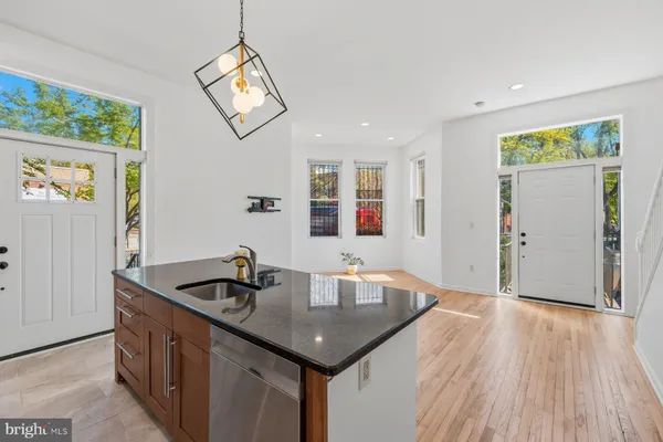 a kitchen with stainless steel appliances kitchen island granite countertop a stove a refrigerator and a wooden floors