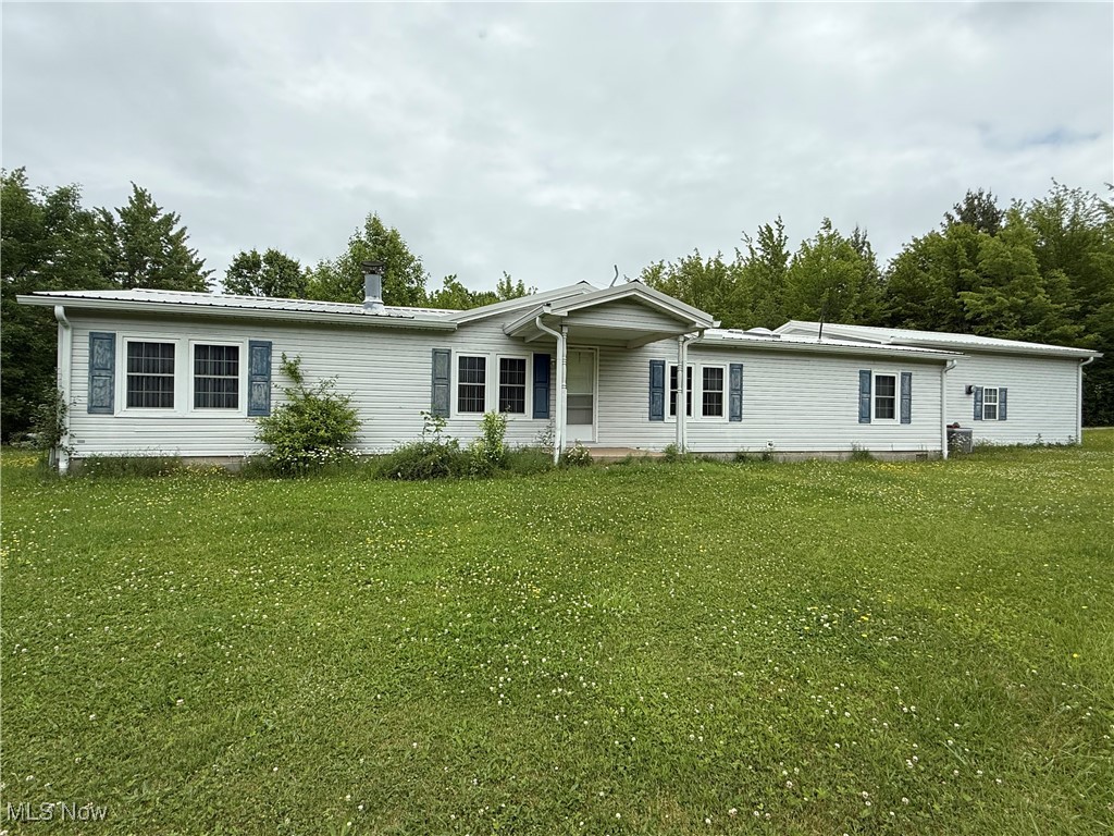 Manufactured / mobile home featuring a front yard and metal roof