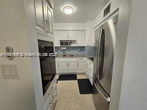 a kitchen with stainless steel appliances a refrigerator a sink a stove and white cabinets