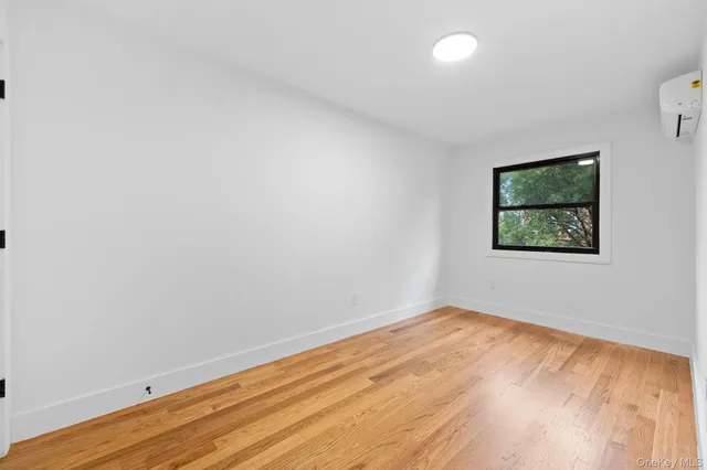 an empty room with wooden floor and window