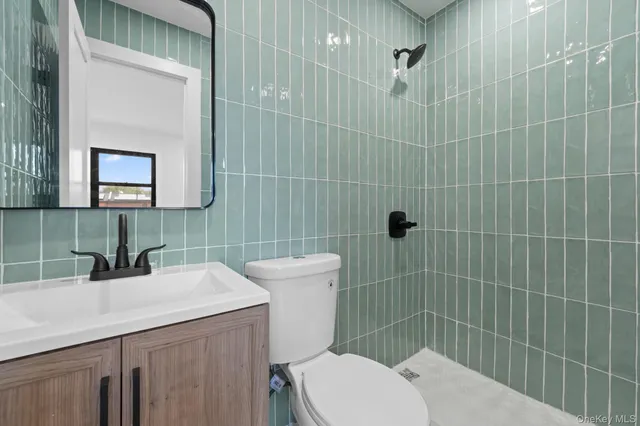 a bathroom with a toilet a sink a mirror and shower