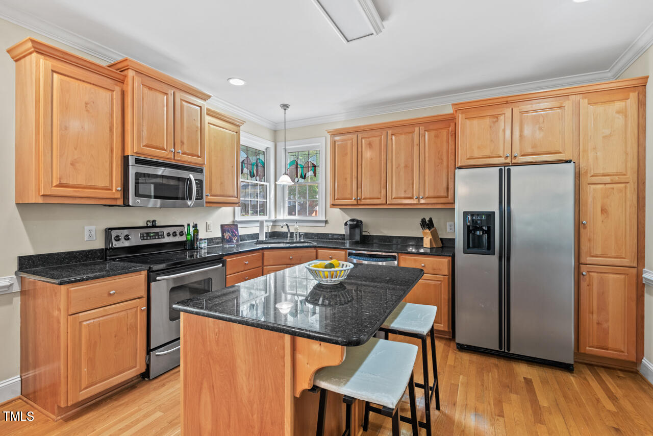 7930 Pine Timber Drive Raleigh, NC 27613 - Photo 21 of 57 a kitchen with granite countertop wooden cabinets a refrigerator a stove a sink and a microwave