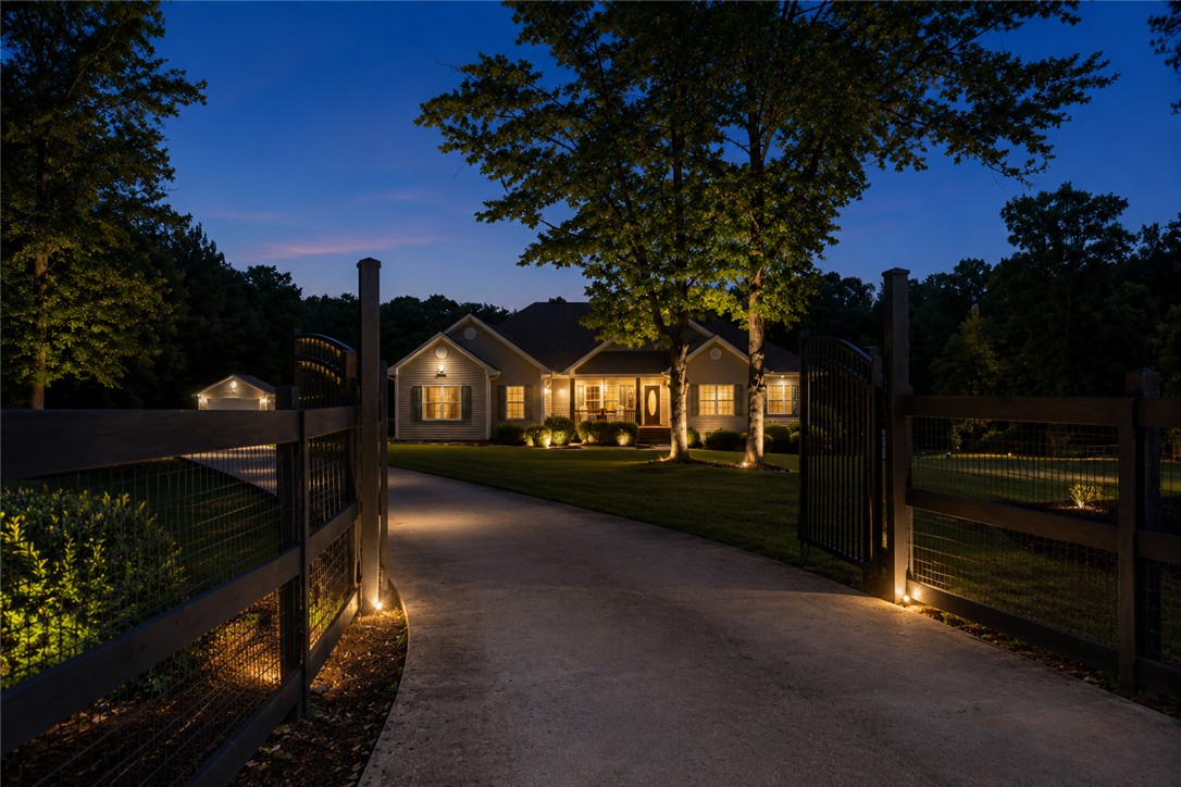 190 Fred Bradford Road Iva, SC 29655 - Photo 28 of 32 This home features a private entrance with gate and a well-lit driveway at dusk.