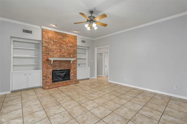 a view of an empty room with a fireplace and a chandelier fan
