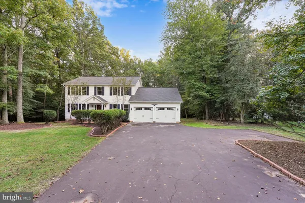 a view of a house with a yard and large trees