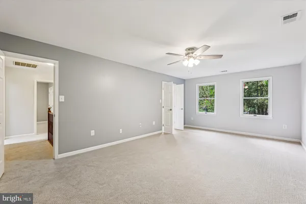 an empty room with windows and ceiling fan