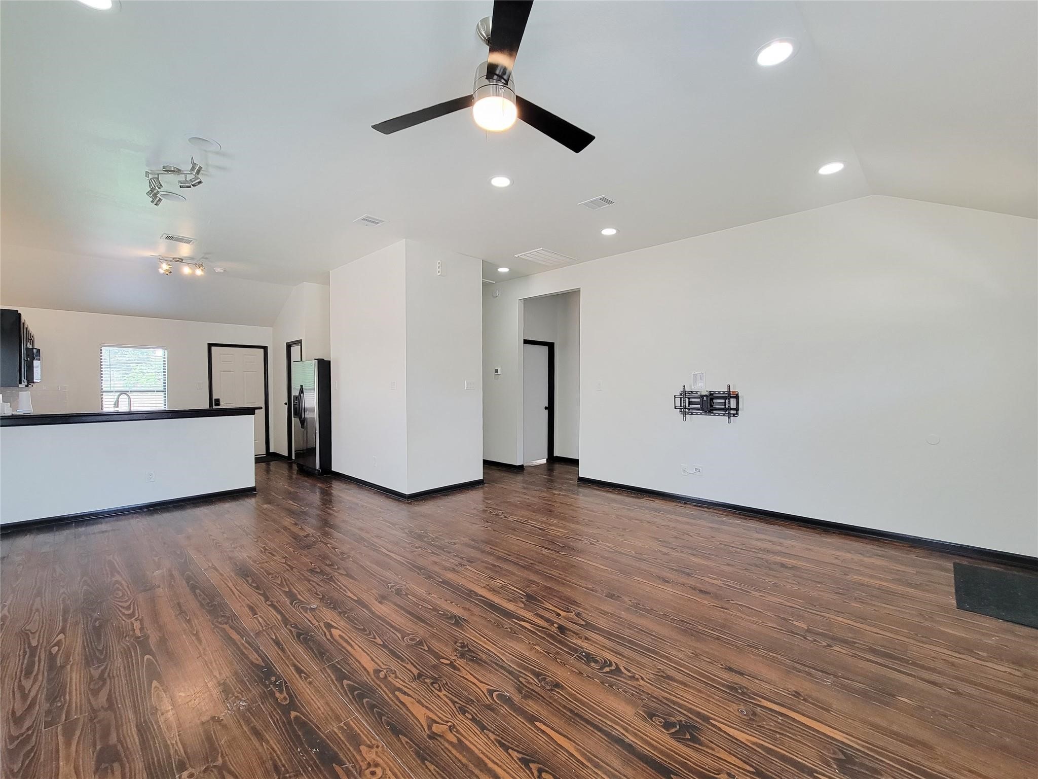 1904 Davis Street Houston, TX 77026 - Photo 6 of 33 an empty room with wooden floor ceiling fan and kitchen view