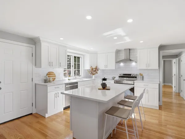 a kitchen with stainless steel appliances a sink a stove a refrigerator cabinets and dining table