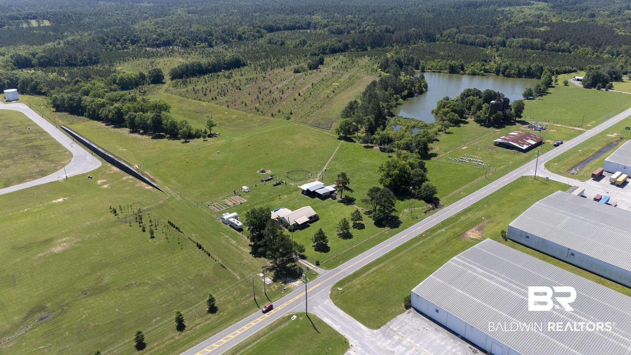 30580 County Road 49 Loxley, AL 36551 - Photo 4 of 32 Expansive green fields featuring a substantial private pond, numerous mature trees, and multiple agricultural structures