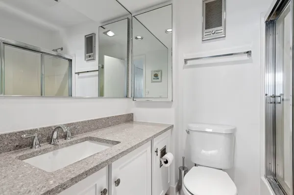 a bathroom with a granite countertop toilet sink and mirror