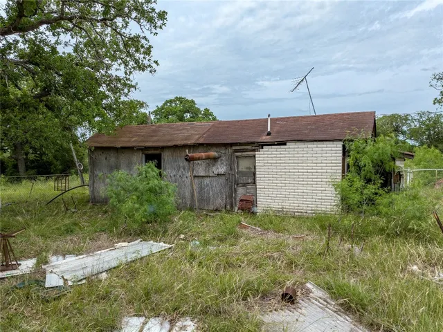 a backyard of a house with plants and large tree