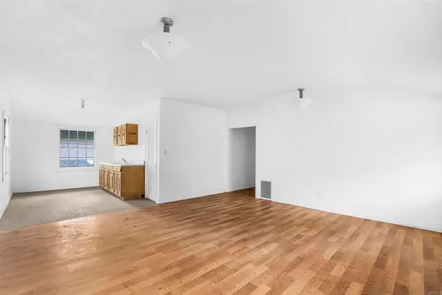 a view of a kitchen with wooden floor and white cabinets