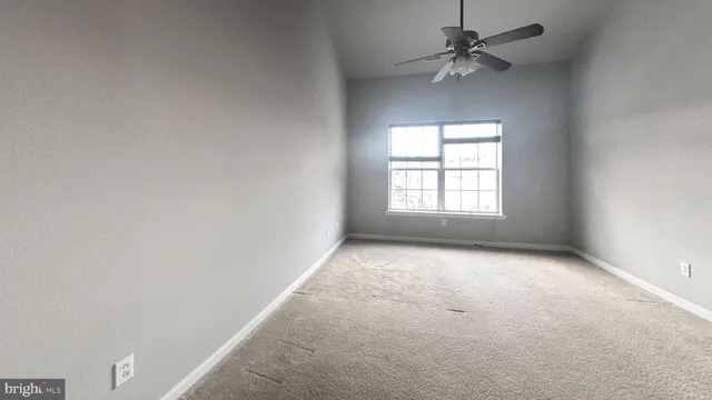 an empty room with a window and a fan