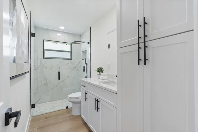 a bathroom with a granite countertop sink a toilet and shower
