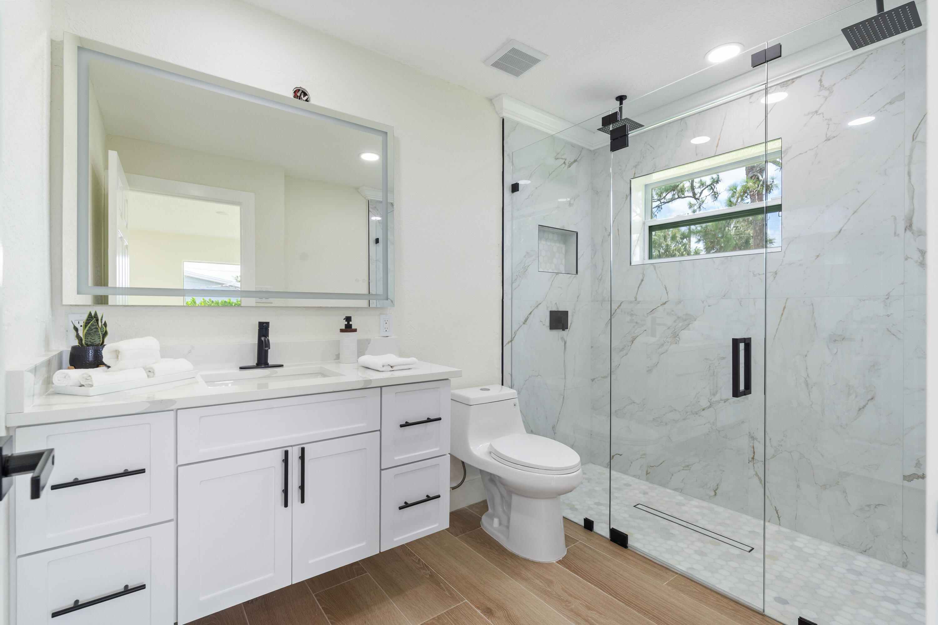 930 Rutherford Lane Haverhill, FL 33415 - Photo 20 of 25 a bathroom with a toilet a sink a glass door a shower and a mirror