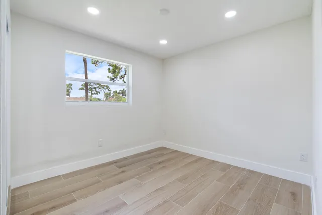 an empty room with wooden floor and window