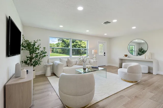 a living room with furniture potted plant and a large window