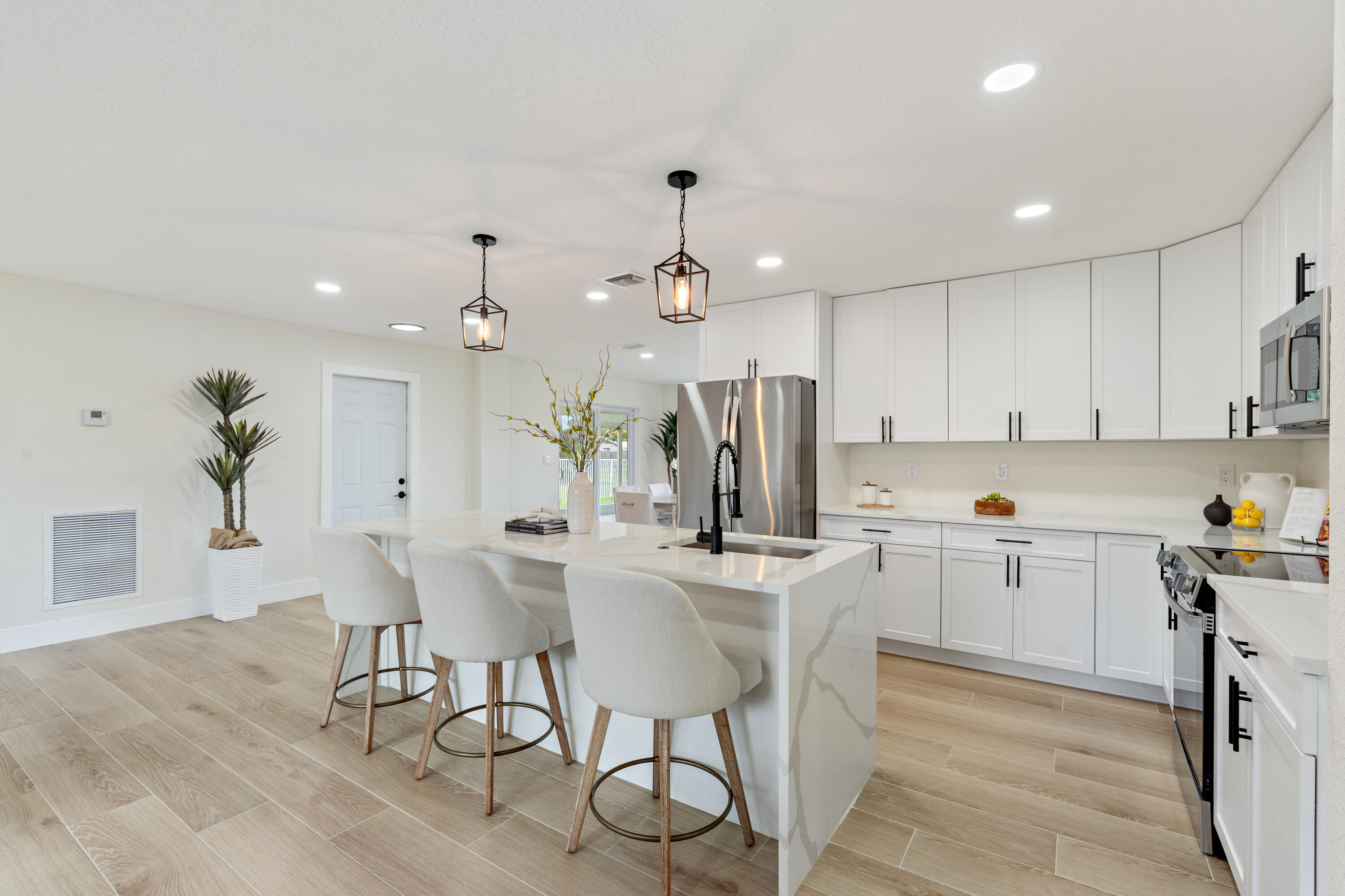 930 Rutherford Lane Haverhill, FL 33415 - Photo 7 of 25 a kitchen with kitchen island a stove a table and chairs in it