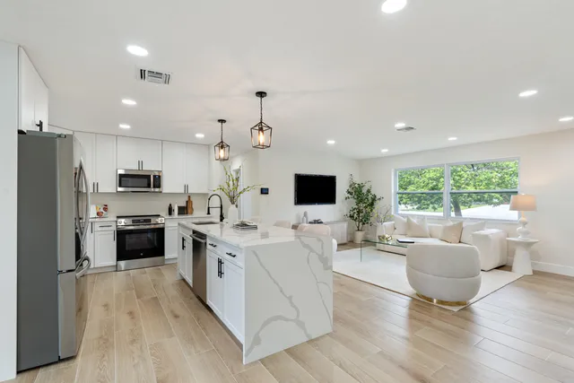 a large living room with stainless steel appliances kitchen island granite countertop a large window and a view of living room