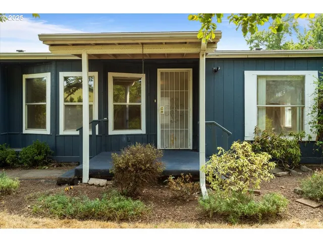 a view of a house with potted plants and a bench