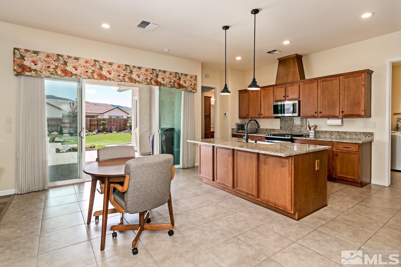 1992 Phaethon Lane Reno, NV 89521 - Photo 3 of 37 a kitchen with stainless steel appliances granite countertop a stove a sink a microwave a dining table and chairs