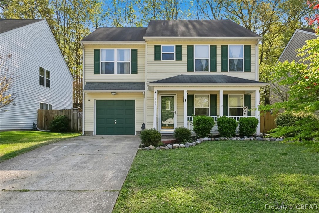 Traditional-style home with concrete driveway, a front yard, a garage, fence, and covered porch