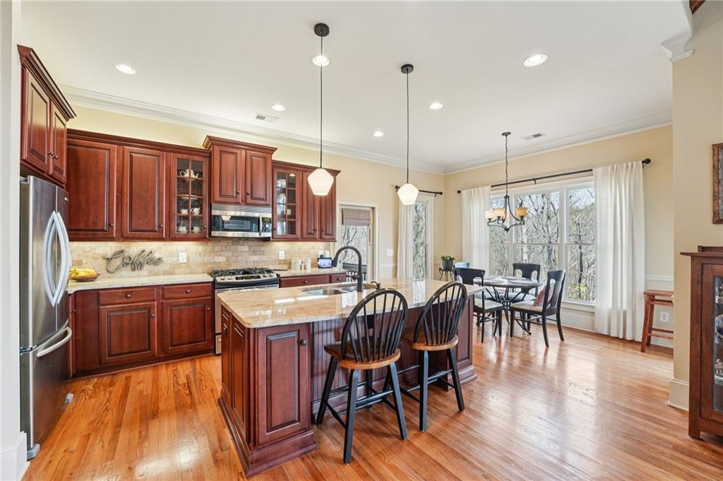 29 Red Trillium Ridge Big Canoe, GA 30143 - Photo 13 of 76 a kitchen with stainless steel appliances granite countertop a stove a refrigerator a kitchen island a dining table and chairs with wooden floor