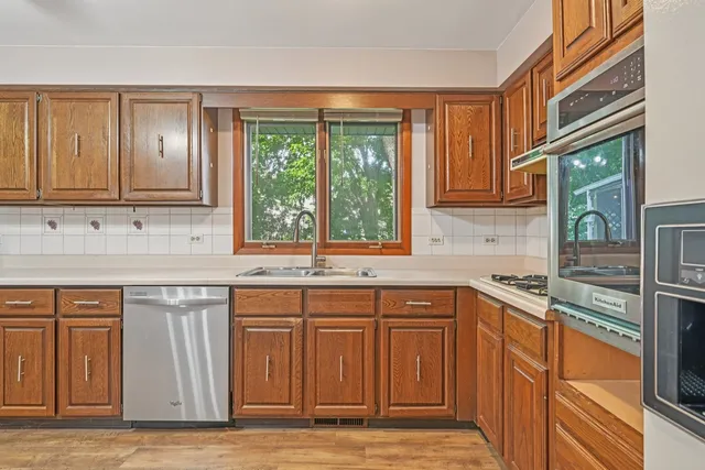 a large kitchen with kitchen island granite countertop a large window a sink stainless steel appliances and cabinets