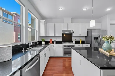 a kitchen with a sink a stove a refrigerator and white cabinets