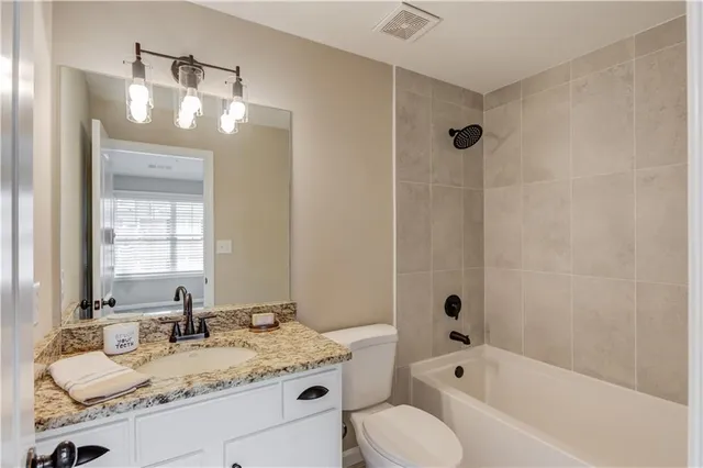 a bathroom with a granite countertop sink mirror toilet and bathtub