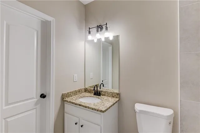 a bathroom with a granite countertop sink a toilet and a mirror