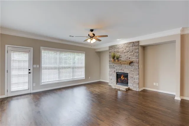 an empty room with wooden floor fireplace and windows