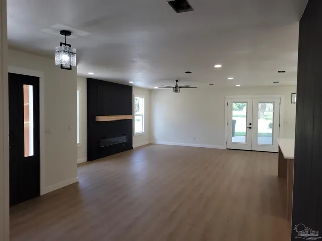 a view of empty room with wooden floor and kitchen