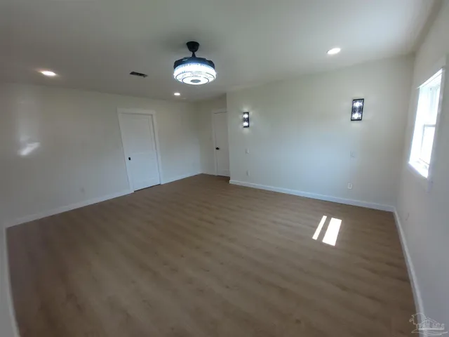 an empty room with wooden floor and windows