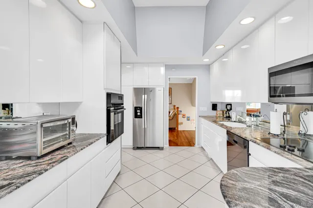a kitchen with stainless steel appliances kitchen island granite countertop a refrigerator oven a sink dishwasher and white cabinets with wooden floor