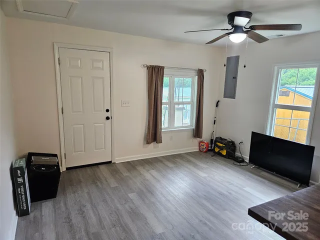 a view of an empty room with a window and wooden floor