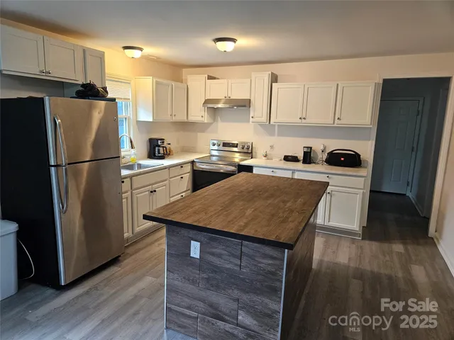 a kitchen with a refrigerator a stove top oven and wooden floor