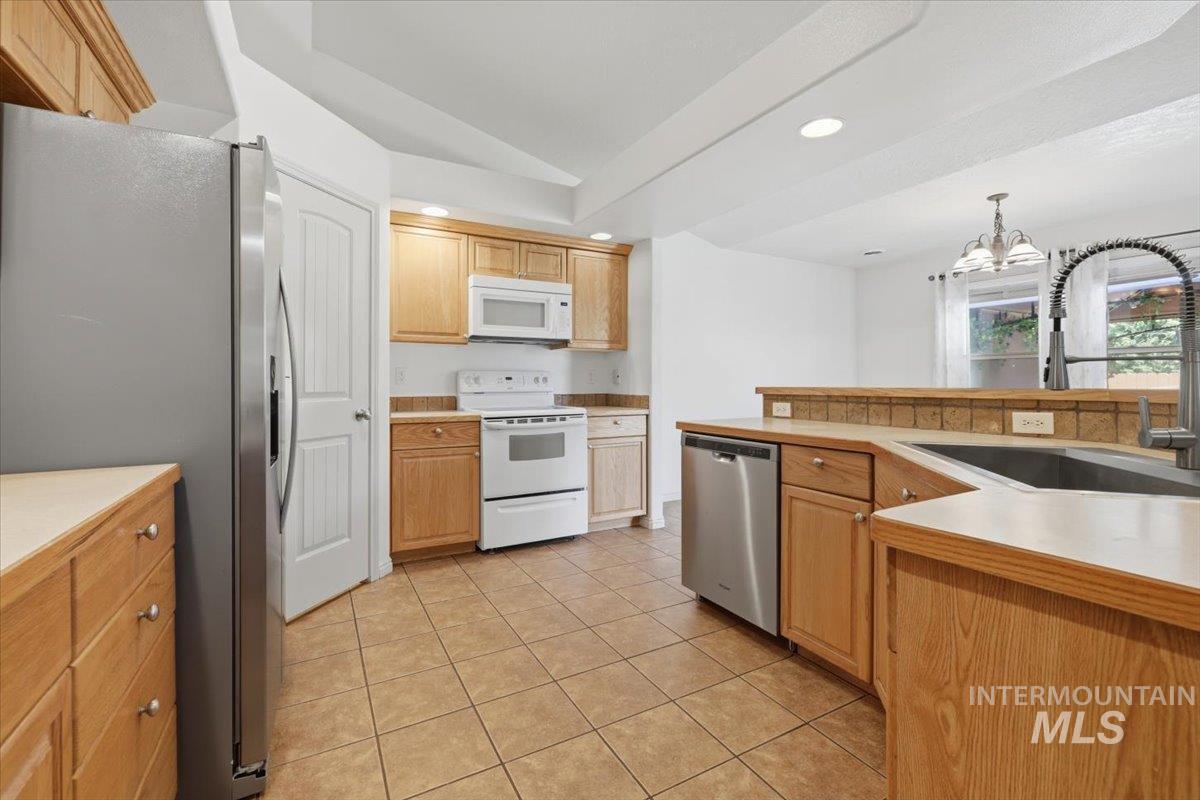 1068 Locksley Street Middleton, ID 83644 - Photo 11 of 30 Kitchen featuring light wood cabinetry, white appliances, stainless steel refrigerator, tile flooring, and a double basin sink with a gooseneck faucet