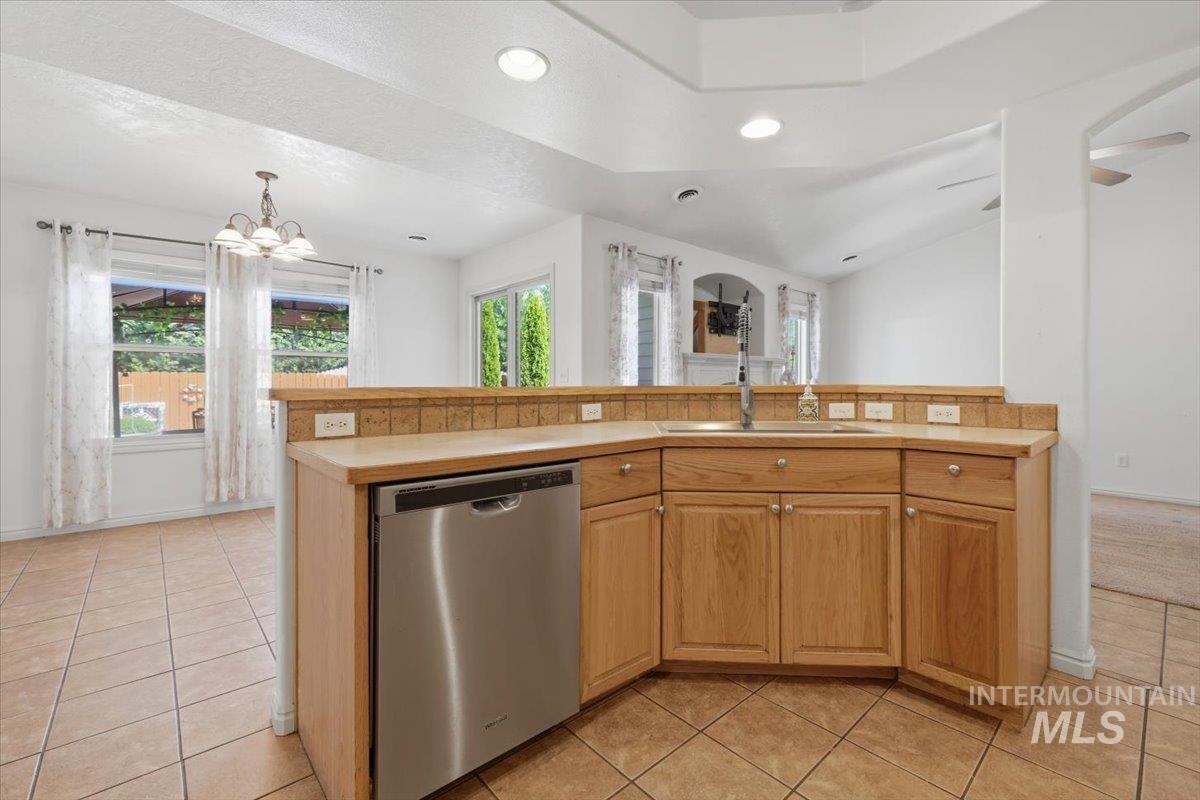 1068 Locksley Street Middleton, ID 83644 - Photo 12 of 30 Kitchen featuring wood-finish cabinetry, stainless steel dishwasher, tile countertop with matching backsplash, and an undermount sink