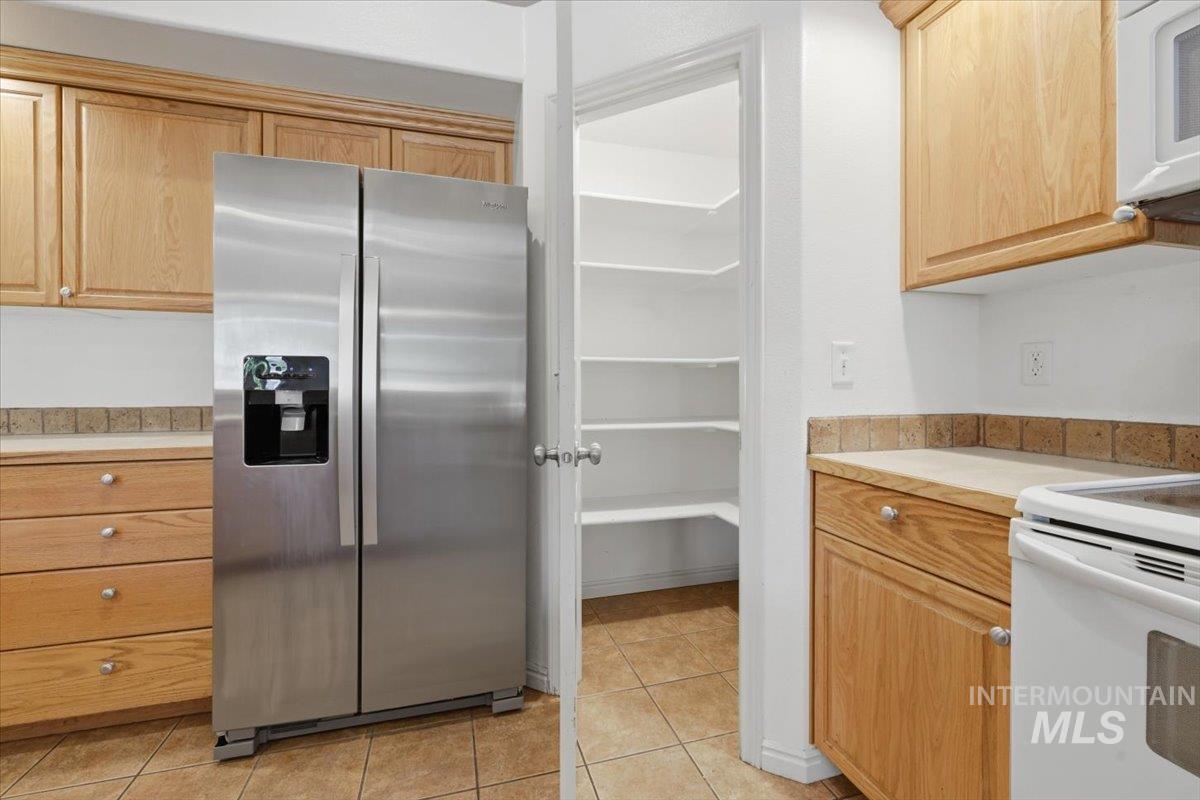1068 Locksley Street Middleton, ID 83644 - Photo 13 of 30 Kitchen featuring wood cabinetry, stainless steel side-by-side refrigerator, tile countertops, and a walk-in pantry with ample shelving