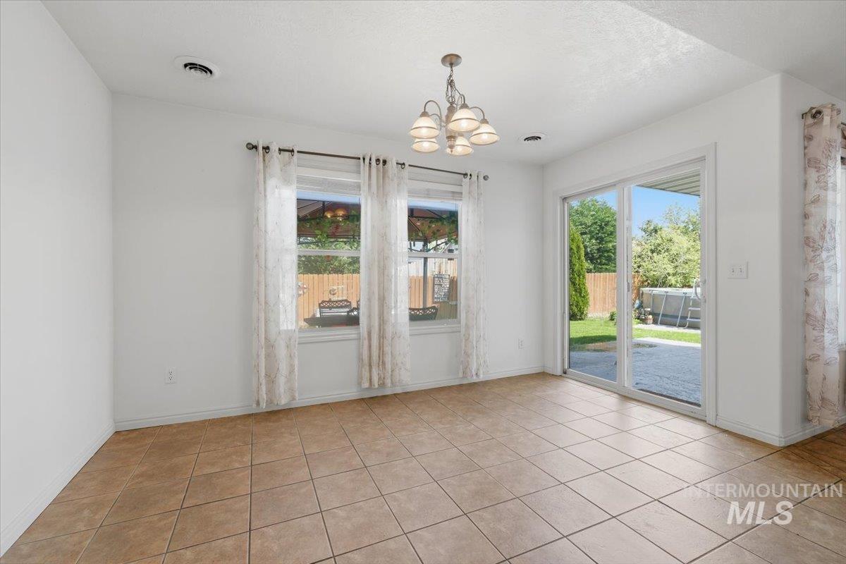 1068 Locksley Street Middleton, ID 83644 - Photo 14 of 30 Bright interior space featuring large tile flooring, a multi-pane window, and a glass sliding door providing direct access to the backyard